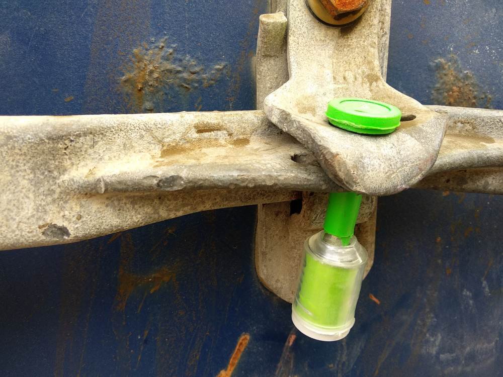 A close-up of a High Security Bolt Seal applied to a container latch, emphasizing the steel pin and locking mechanism.