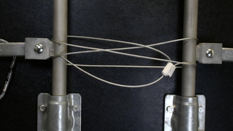 A flexible cable seal wrapped around the latches of a semi-truck trailer door