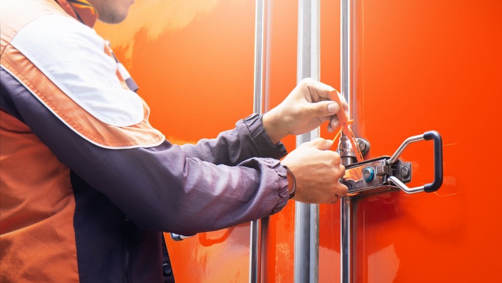 A clear, instructional photo showing a person's hands pulling firmly on a newly applied security seal to confirm it is locked securely.
