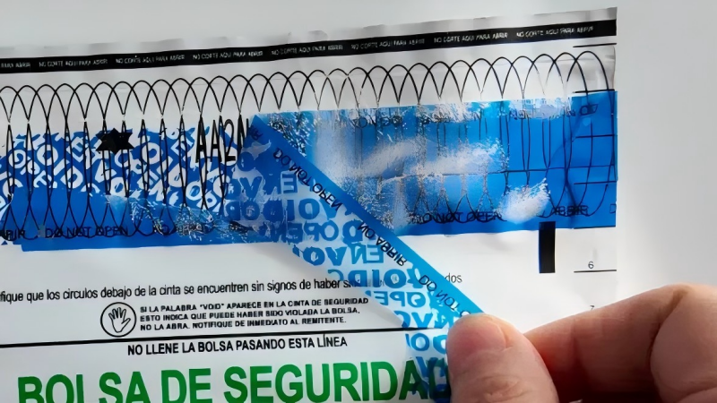 A tamper-evident bag that has been peeled open, revealing the bright red "VOID OPEN" message left behind by the security tape.