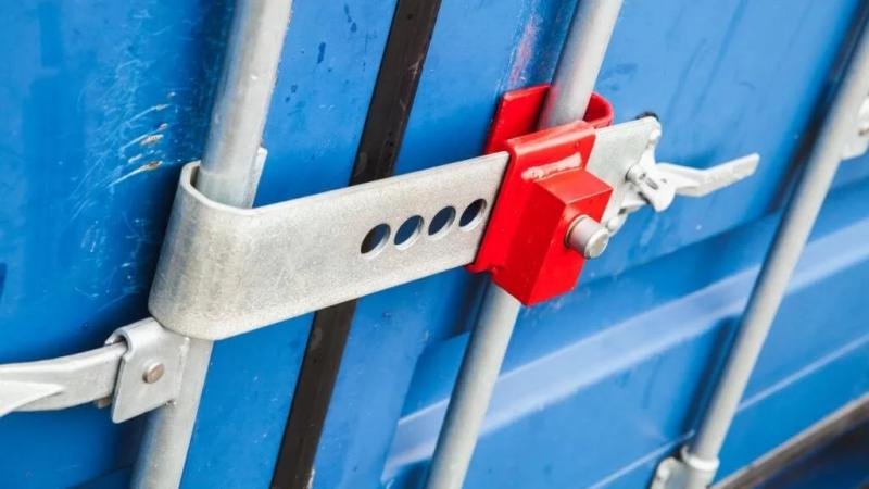 Barrier Seal for Physical Defense A massive, heavy-duty steel bar lock (a type of barrier seal) secured across the central locking bars of a shipping container.