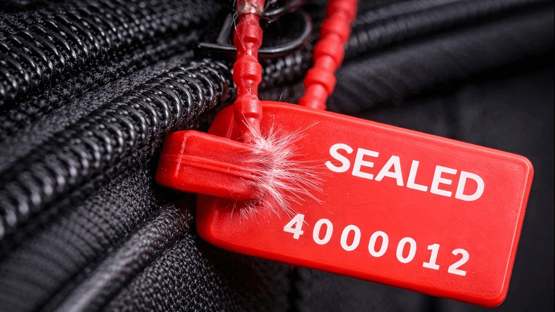 Inspecting a used bag seal for tampering Showing tell-tale signs of tampering on a seal: white stress marks from bending and tiny scratches near the insertion point.