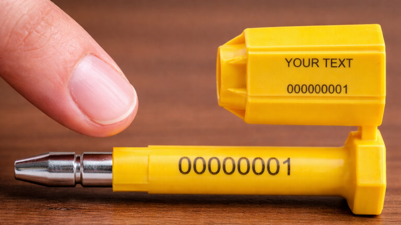 A macro shot of a laser-engraved, unique serial number on a security seal, with a finger pointing to it to emphasize its importance.