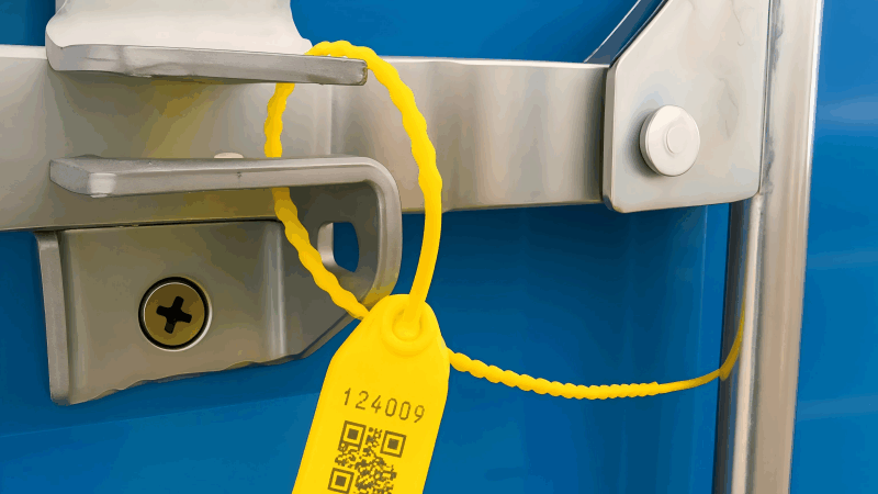 A bright yellow variable length plastic seal applied to a truck door, highlighting the serial number.