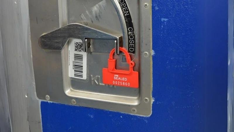A bright red all-plastic padlock seal on a warehouse tote, showing its use as a visual security indicator.